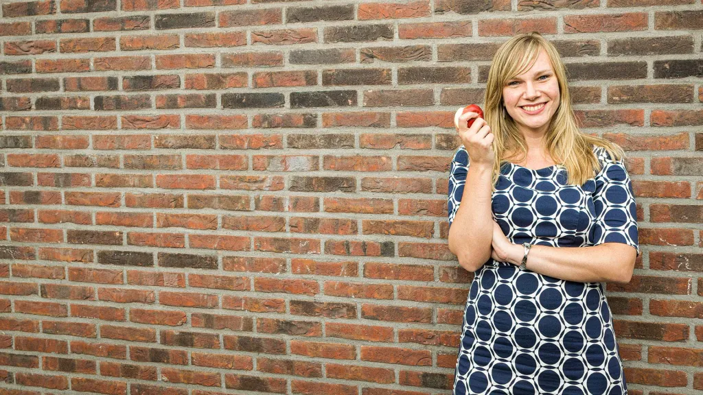 Vrouw die een appel eet bij een muur