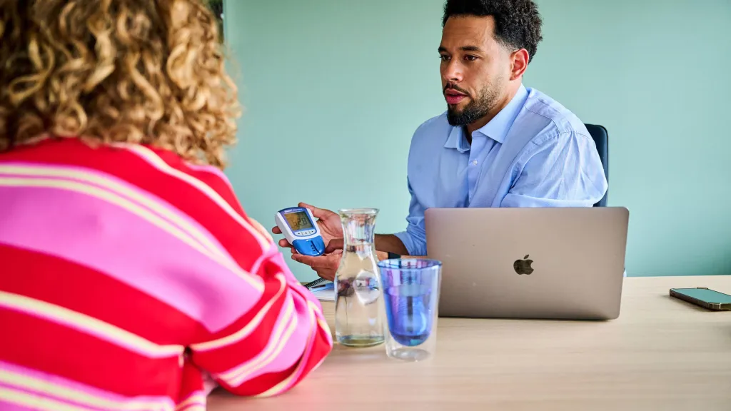 Vitaliteit- en gezondheidsdeskundige doet meting bij met medewerker.