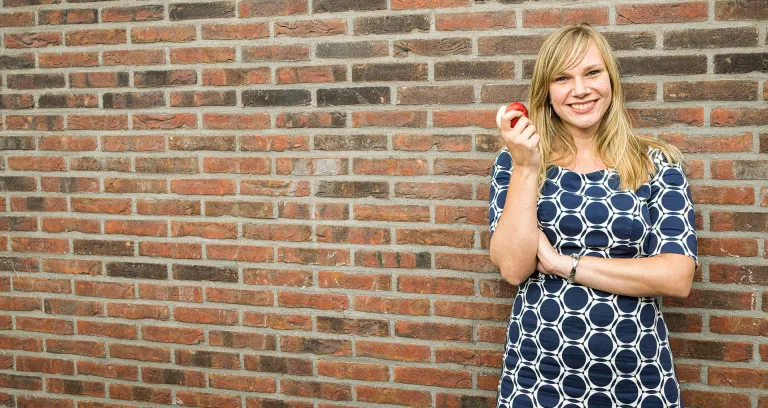 Vrouw die een appel eet bij een muur