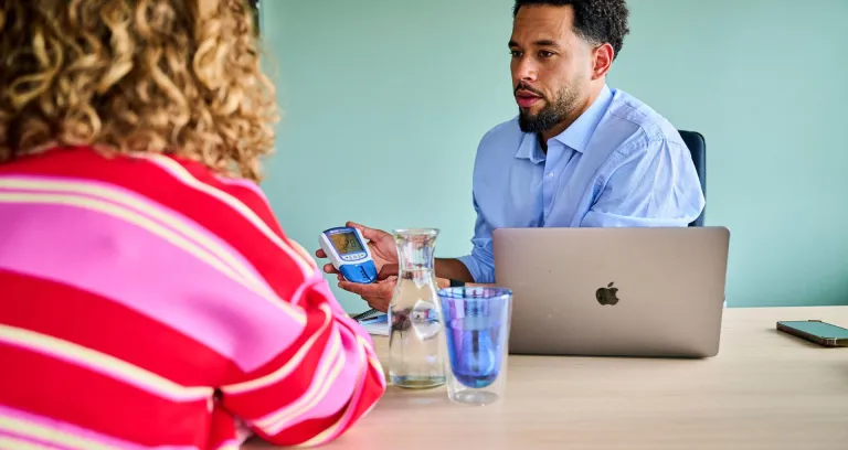 Vitaliteit- en gezondheidsdeskundige doet meting bij met medewerker.