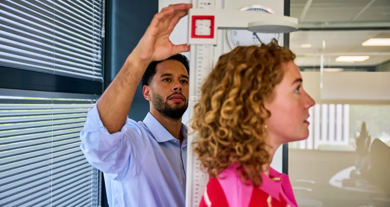 Vitaliteit- en gezondheidsdeskundige meet lengte van medewerker.